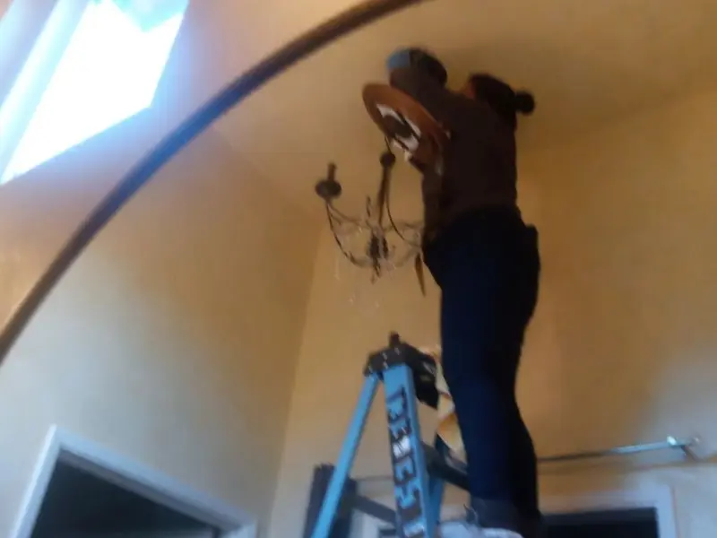 Electrician installing a chandelier in a Monticello residence